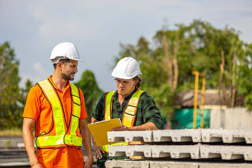 Manufacturing executive reviewing sales performance data on a tablet A manufacturing plant manager or executive stands on a production floor reviewing sales and revenue data on a tablet, representing the gap between operational visibility and sales visibility.